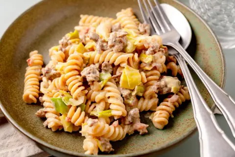 Herzhafte Hackfleisch Lauch Pfanne mit Spiralnudeln, cremig und appetitlich auf einem rustikalen Teller angerichtet.