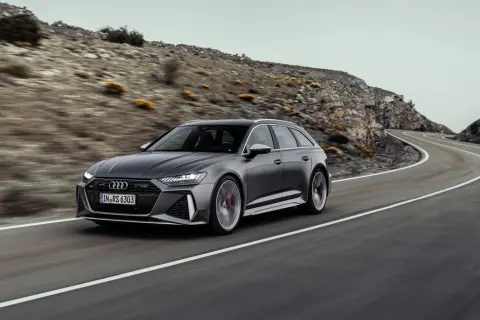Audi RS6 Avant gris en movimiento en una carretera sinuosa, demostrando su velocidad máxima en un paisaje montañoso.