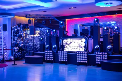 Efektowne atrakcje na 18 urodziny na sali: DJ, balony, światła i ekran z życzeniami.