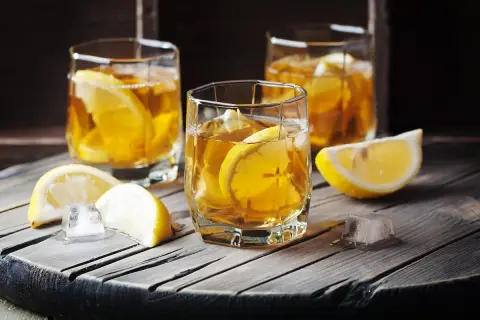 Trzy szklanki z bursztynowym napojem, lodem i plasterkami cytryny. Czy to Metaxa? Co to jest Metaxa?