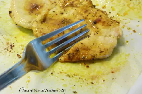 Un succulento petto di pollo in padella morbido, dorato e speziato, pronto per essere gustato con una forchetta.