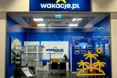 Witryna biura podróży Wakacje.pl z logo, wystawami ofert i dekoracjami wakacyjnymi.