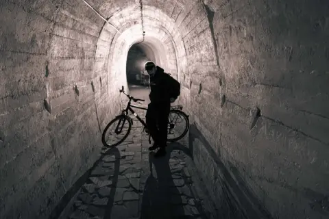 Mężczyzna z rowerem w tunelu. To może być początek jego przygody na podziemnej trasie rowerowej.