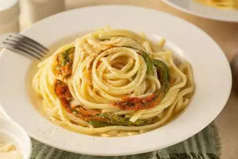 Un piatto di spaghetti conditi con delicati fiori di zucca, un classico della cucina italiana.