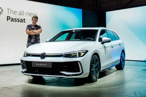 Mężczyzna stoi obok białego kombi, prezentując nowy Passat 2024.