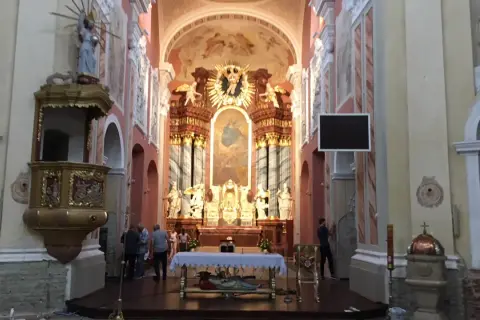 Wnętrze kościoła w Trzemesznie z ołtarzem głównym, amboną i wiernymi.