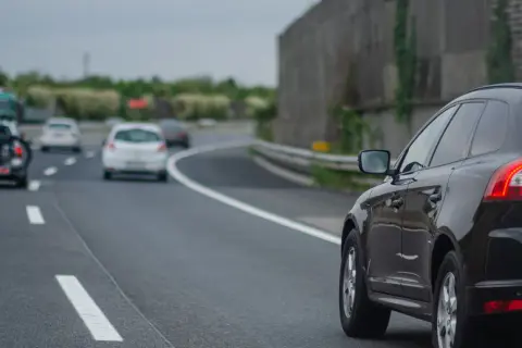 Czarny SUV na autostradzie, obok białe samochody. Kiedy można wyprzedzać z prawej strony? Gdy lewy pas jest wolny, a prawy służy do wyprzedzania.