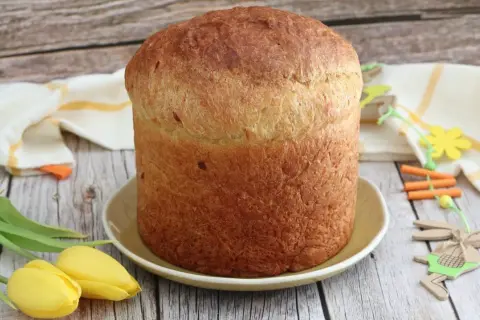 Gâteau de Pâques italien doré, prêt à être décoré d'œufs durs. Tulipes jaunes et décorations de lapin apportent une touche festive.