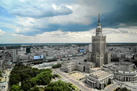 Warszawski Pałac Kultury i Nauki góruje nad miastem, ukazując swoją imponującą wysokość na tle chmur.