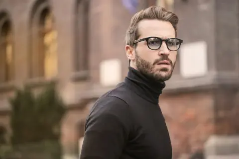 Mann mit Brille und Bart, dessen old money style herren haare perfekt sitzen.
