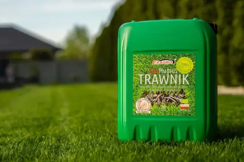 Zielony kanister z napisem "Humus Trawwnik" na tle bujnej, zielonej trawy. To naturalny nawóz, który pomoże Twojemu trawnikowi rozkwitnąć.