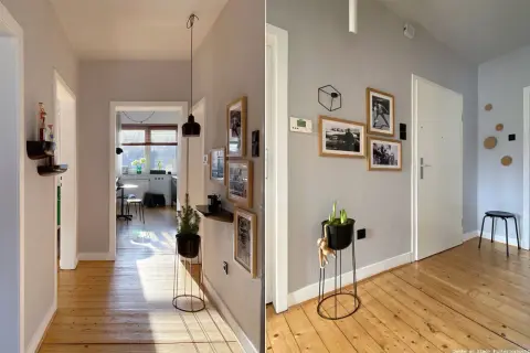Flur mit Holzboden und grau gestrichenem Wanddesign. Bildergalerie und Pflanzen zieren die Wände.