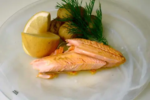 Hel regnbåge i ugn, serverad med småpotatis, citron och dill. En vacker och smakrik rätt.