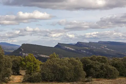 Paisaje montañoso con formaciones rocosas afiladas, típico de fotos de ojo Guareña. Nubes blancas y cielo azul.