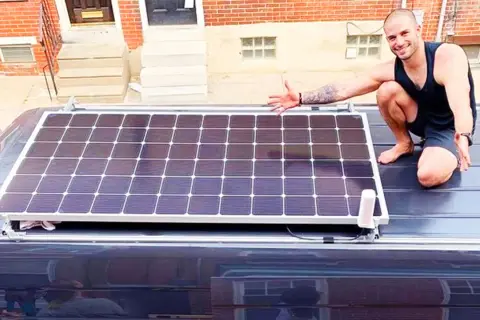 Hombre muestra cómo conectar dos placas solares en el techo de una furgoneta.