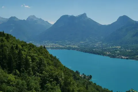 Vue panoramique du lac d'Annecy, ses eaux turquoise bordées de montagnes verdoyantes. Idéal pour un tour du lac Annecy en km.