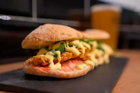 Un bocadillo generoso con pollo crujiente, salsa y rúcula, uno de los mejores bocadillos de Zaragoza.