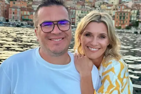 Anna Lewandowska i jej mąż cieszą się wakacjami nad wodą, w tle kolorowe kamienice.