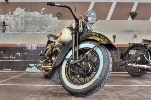 Klasyczny motocykl z białymi bokami opon, stojący w garażu.