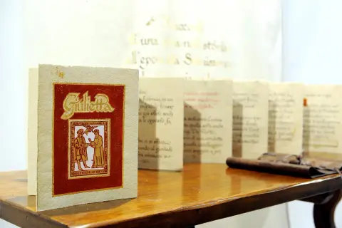 Libri con copertina rossa e dorata, "Giulietta", e altri volumi con testo calligrafico, esempi di prodotti artigianali Friuli Venezia Giulia.