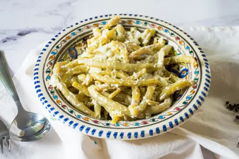 Ein cremiger Bohnensalat mit Sahne, serviert in einer bunten Schüssel. Ein leckeres Gericht, das zum Genießen einlädt.