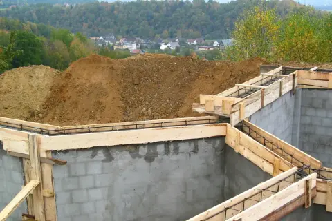 Fundamenty domu w budowie, zbrojenie i szalunki gotowe do zalania betonem. Pozwolenie na budowę wydane, marzenia o domu nabierają kształtów.