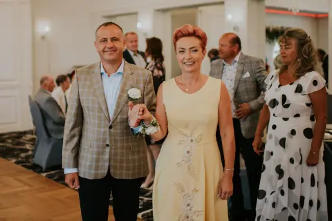 Elegancka sukienka dla mamy panny młodej plus size w kolorze pastelowej żółci, ozdobiona delikatnymi kwiatowymi aplikacjami.