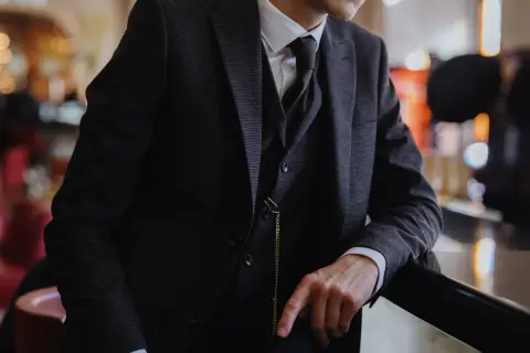 Uomo con completo gessato scuro, gilet e cravatta, un vero esempio di stile italiano.
