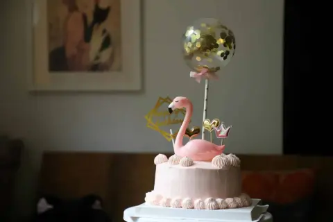 Różowy tort z flamingiem i złotym balonem z konfetti. Inspiracja, jak udekorować tort na przyjęcie.