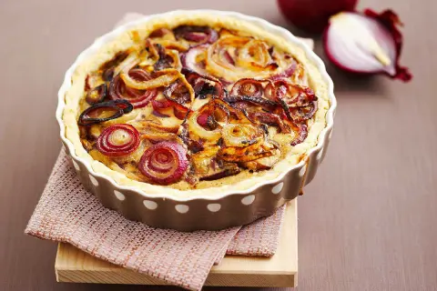 Tarte à l'oignon dorée et appétissante, garnie d'oignons caramélisés et d'une pâte croustillante. Un délice visuel et gustatif.