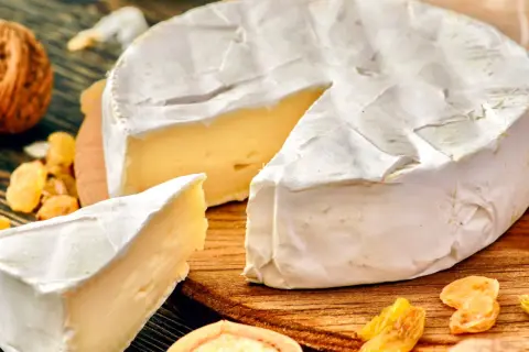 Kawałek sera camembert z białą pleśnią, orzechami i rodzynkami. Czy ser camembert jest zdrowy? W umiarkowanych ilościach może być częścią zbilansowanej diety.