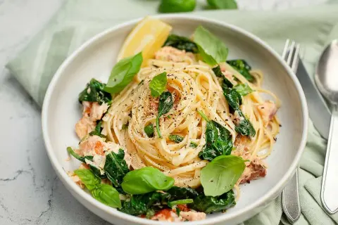 Krämig pasta med lax och spenat, toppad med färsk basilika och en citronklyfta. Smaken påminner om en mild citrusfrukt ugli.