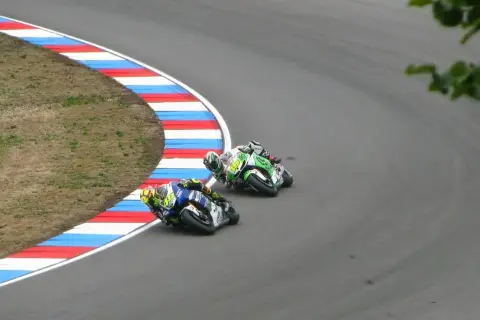 Dwóch motocyklistów ściga się na zakręcie toru wyścigowego.