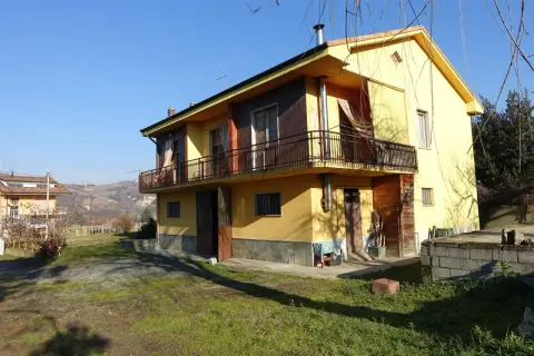 Casa gialla con balcone e vista collinare, un esempio di case economiche in campagna.