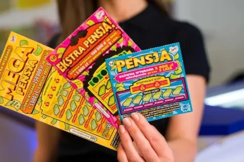 Kobieta trzyma zdrapki lotto: "Mega Pensja", "Ekstra Pensja" i "Pensja". Sprawdź zasady gry, by wygrać ekstra pensję!