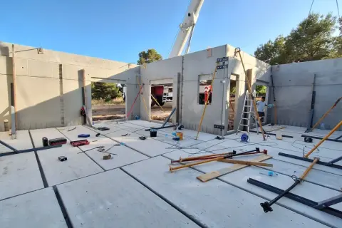 Construcción de una casa prefabricada en Madrid. Se ven paneles de hormigón, puntales y herramientas.