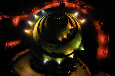 Nocne oświetlenie Kopca Kościuszki tworzy magiczną atmosferę. Kręte ścieżki i zieleń kopca lśnią w blasku reflektorów.