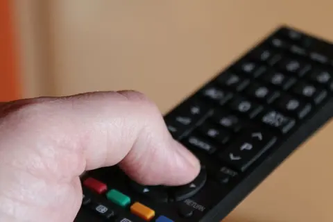 Dłoń trzymająca pilot do telewizora Samsung, naciskająca przyciski.