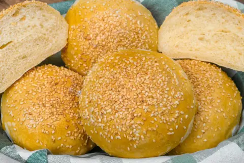 Koszyk pełen pysznych, złotych bułek bez drożdży, posypanych sezamem. Idealne na burgery lub jako dodatek do posiłku.