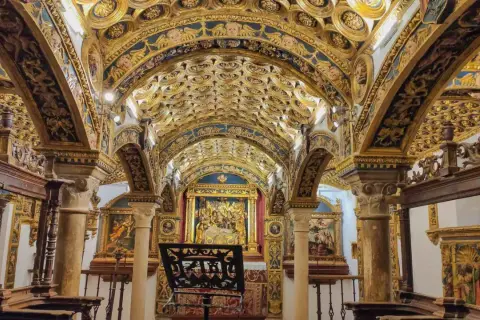 Interior de una capilla ricamente decorada con techos abovedados dorados y azules, pinturas y un altar. Caminos de pasión que invitan a la contemplación.