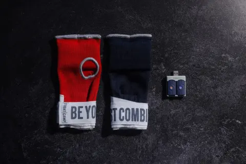 Red and navy hand wraps with "BE YOUR BEST COMBAT" text, and a USB sensor for a boxing match train.