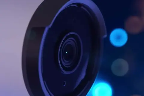 Gros plan sur l'objectif d'une caméra de surveillance, avec des lumières bleues floues en arrière-plan, évoquant le stockage vidéo surveillance.