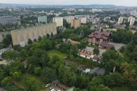 Widok na osiedle mieszkaniowe i kościół, przypominający o historii Krakowa.