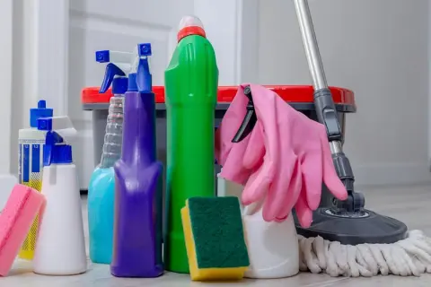 Un surtido de 25 productos de limpieza del hogar, incluyendo botellas rociadoras, esponjas, guantes rosas y un trapeador, listos para dejar tu casa reluciente.