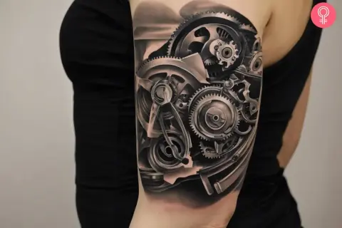 Tatuaż mechanicznej ręki z widocznymi zębatkami i elementami maszynowymi.