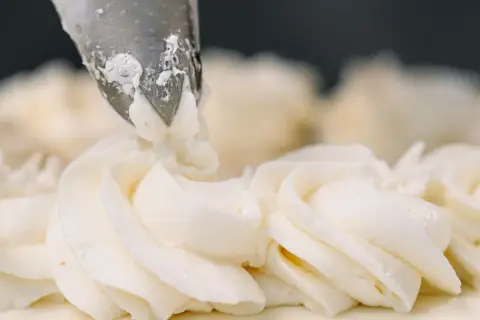 Dekorowanie tortu kremem patissiere za pomocą rękawa cukierniczego.