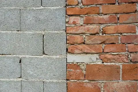 Muro de bloques de hormigón gris a la izquierda, ladrillos rojos desgastados a la derecha.