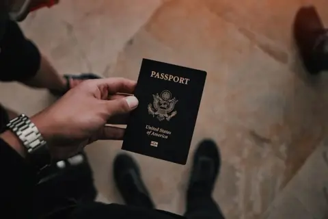 Dłoń trzyma czarny paszport USA. Czas na złożenie wniosku o paszport i rozpoczęcie podróży.