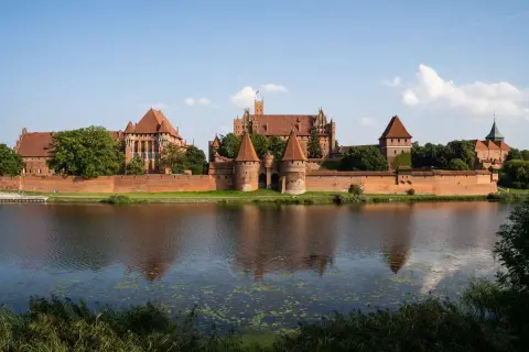 Potężny zamek w Malborku, odbijający się w wodzie. Ciekawostki o jego historii i architekturze budzą podziw.