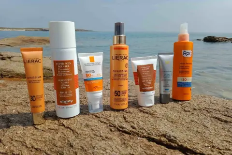 Des crèmes solaires Lierac, Sisley, La Roche-Posay, Skinceuticals et Roc sur des rochers. Elles servent à protéger la peau des rayons UV et à prévenir le vieillissement cutané.